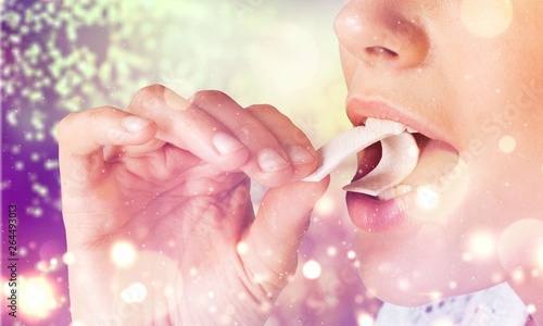 Close-up view of young woman putting chewing gum in her mouth