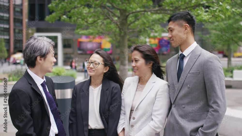 Portrait of smart Asian business team talking amongst themselves out in the city Portrait of smart Asian business team talking amongst themselves out in the city