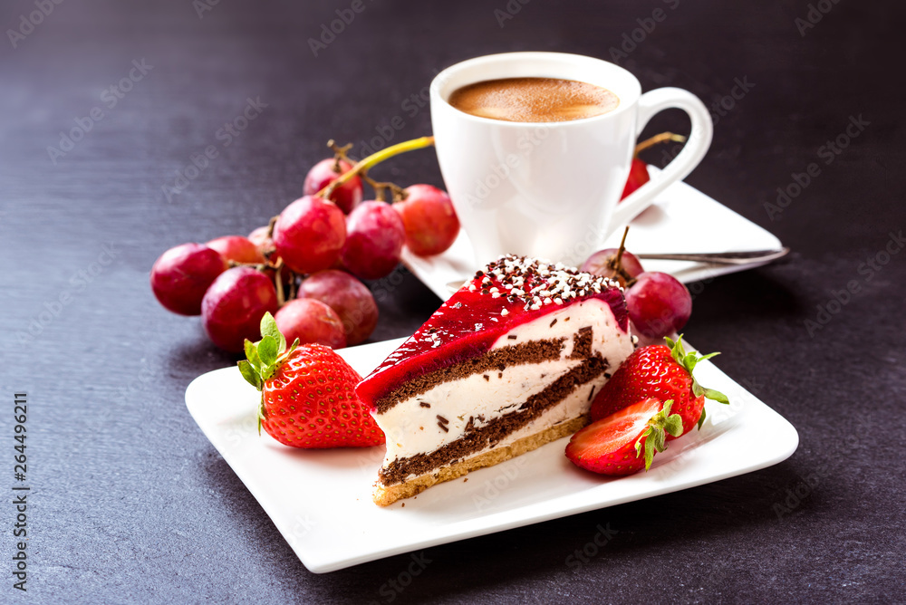 Breakfast. Dessert and coffee. A cup of hot coffee with crema, cake and fruit. Grapes, strawberries and fruit cake. Still life on a dark background