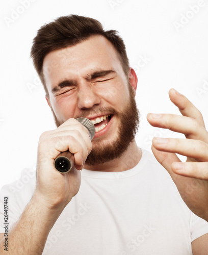 young bearded man in white shirt singing in microphone