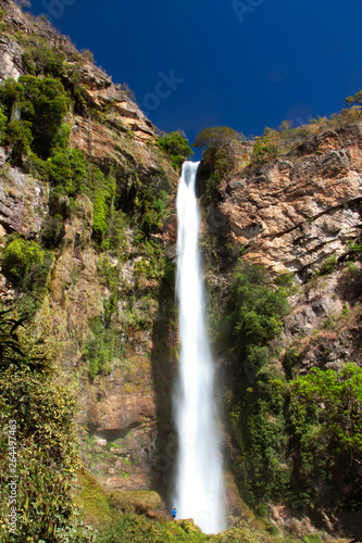 A very high waterfall against a vertical mountain face with a small boy for reference. Brazilian Savannah. 