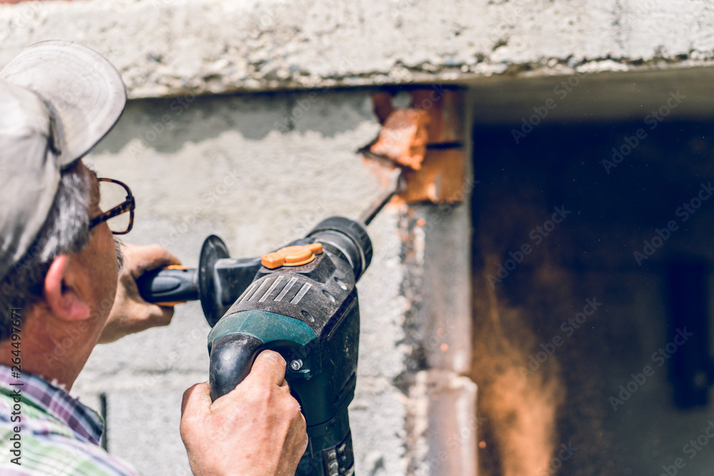 Construction industry worker using pneumatic hammer drill to cut the wall concrete brick drilling holes, close up Construction industry worker using pneumatic hammer drill to cut the wall concrete brick drilling holes, close up