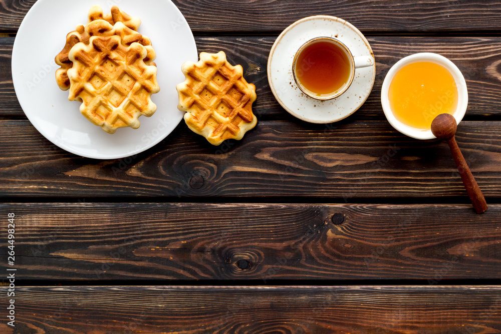 Homemade Viennese waffles with honey and tea, flatware on wooden background top view make-up