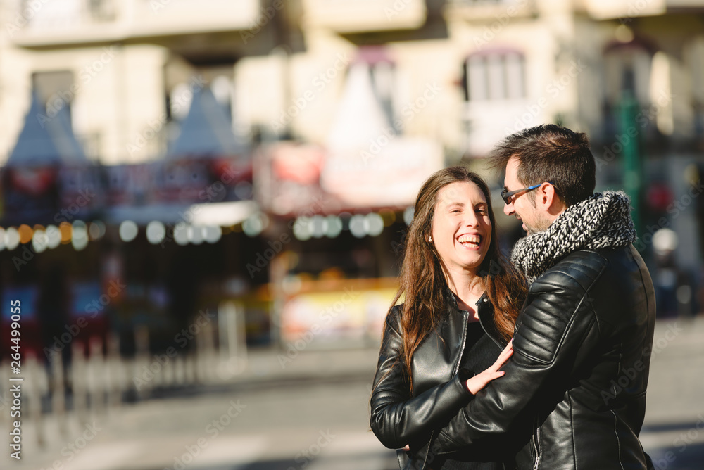 Couple in love embraced in an urban scene, with unfocused background and copy space.