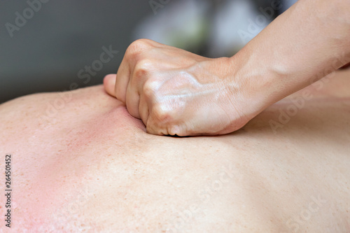 Close-up of a female therapist applying massage with her fists on the back of a woman lying down.