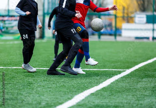 Boys at black red sportswear run, dribble, attack on football field. Young Soccer players with ball on green grass. Training, football, active lifestyle for kids 