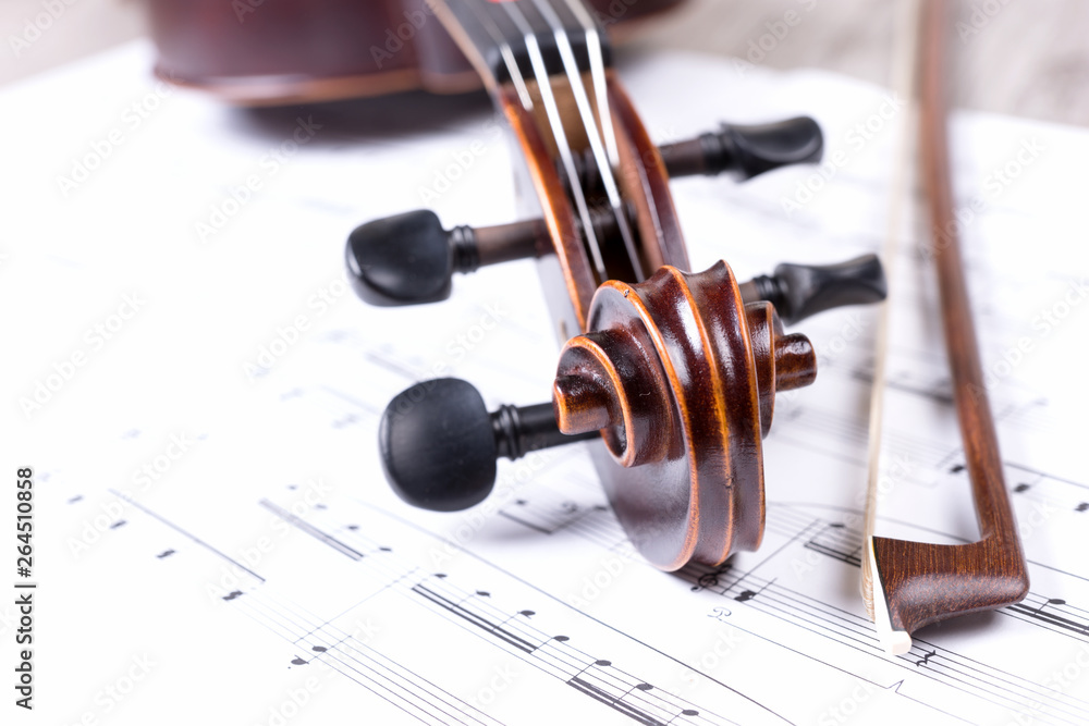Naklejka premium Scroll of the classical violin on music notes. Head of vintage violin