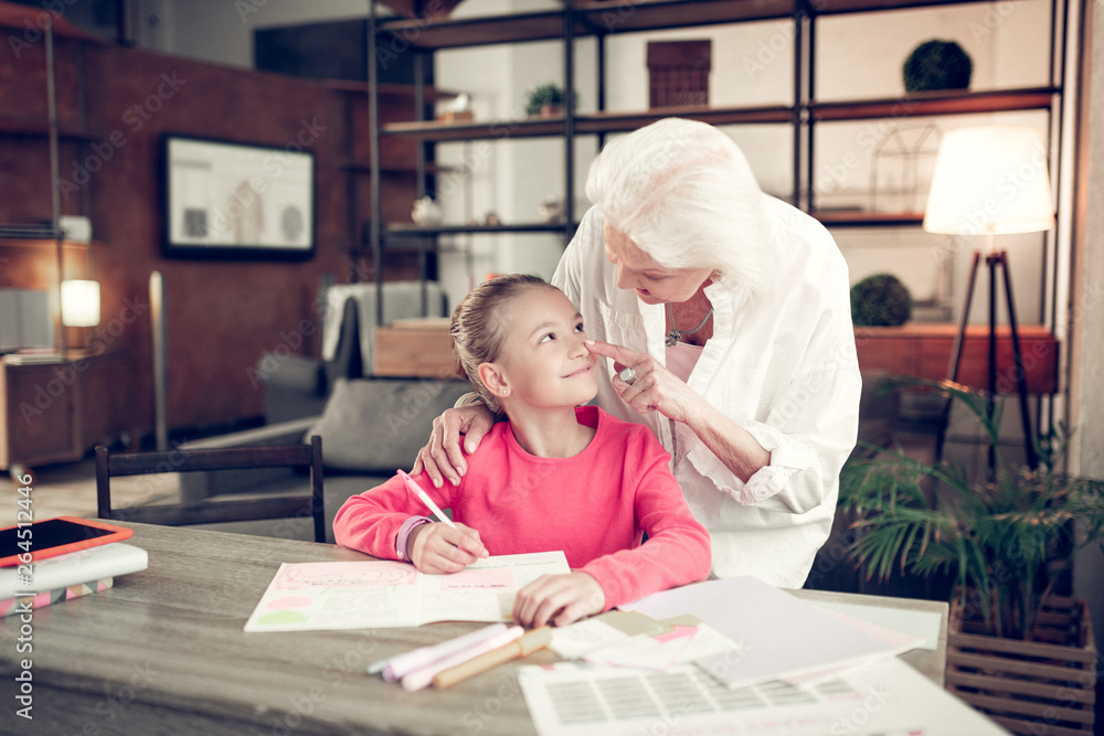 Grey-haired granny touching nose of her lovely cute girl Grey-haired granny touching nose of her lovely cute girl