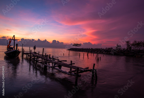 The background of the morning sunrise scenery by the sea, the fishing boats parked in the blurred beauty of the sea breeze that passes through, is the beauty of nature during traveling.