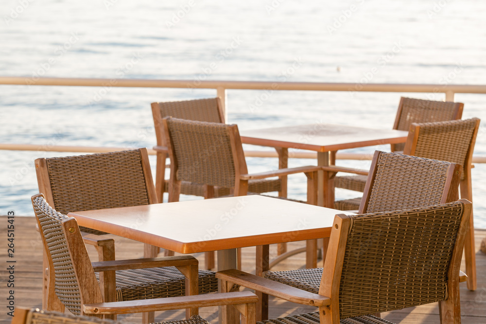 Tables in cafe. Summer sunrise on coast, Corfu island, Greece. Beach with Sunbeds and umbrellas with perfect views of the mainland Greece mountains.