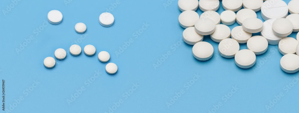 Banner. On the right a lot of round white tablets on a blue background, on the left of the tablets lined with sad emotion
