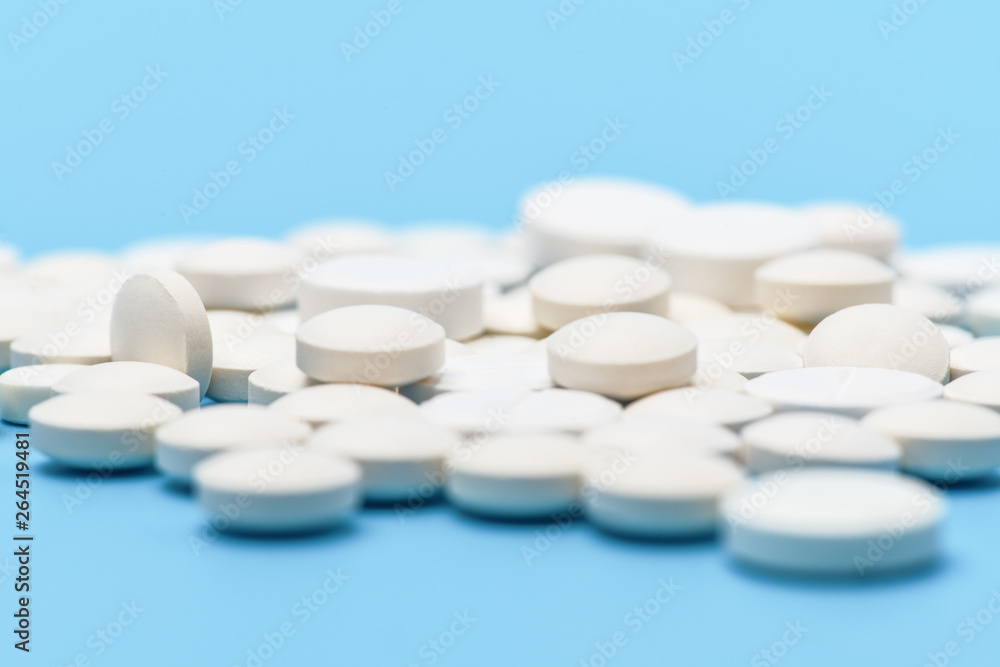 .Close-up of lots of white round pills on blue background. Medical background .