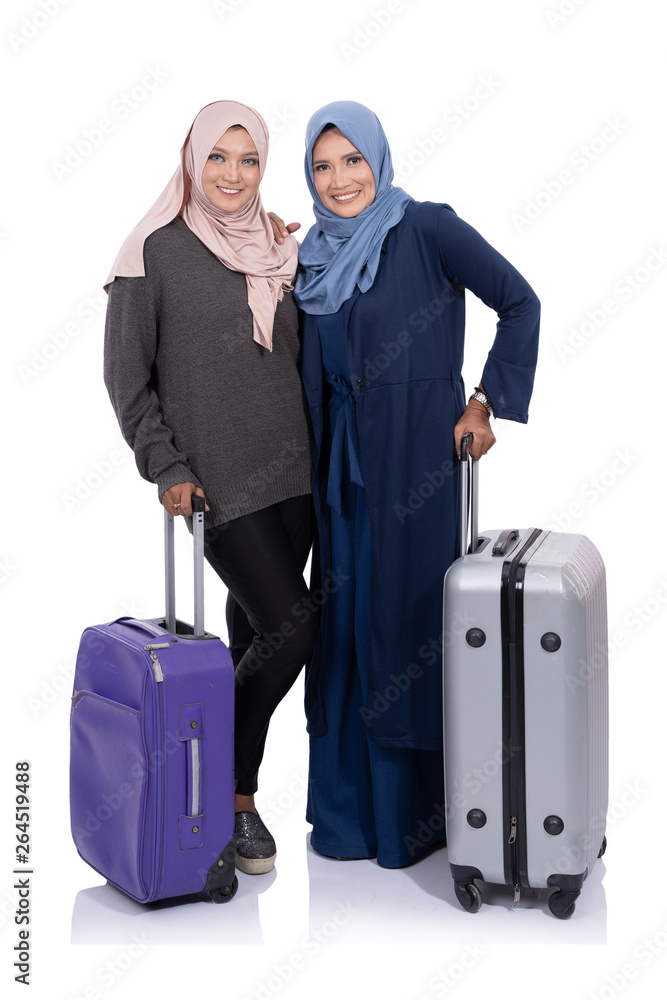 two smiling asian woman hijab with suitccase looking at camera isolated over white background two smiling asian woman hijab with suitccase looking at camera isolated over white background