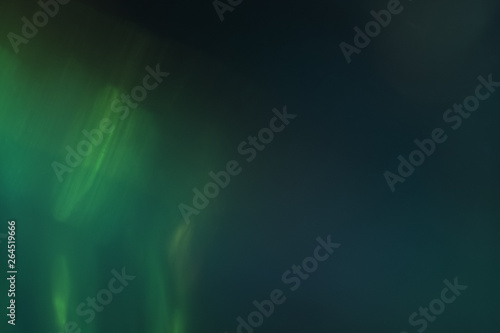 Blurred emerald green lights on dark background. Defocused lens flare glow. Bokeh effect. © golubovy