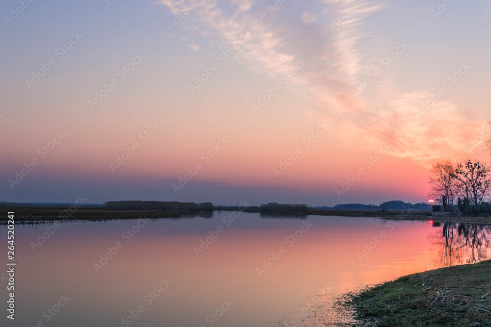Peaceful landscape with the colorful sunrise over the river