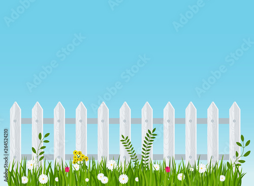 A wooden fence, a hedge near with a flower bed.