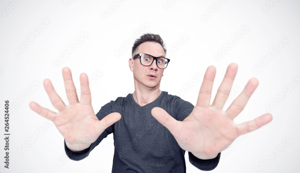 Naklejka premium Man in a black T-shirt and glasses is afraid, making stop with his hands. Deep fear concept emotion