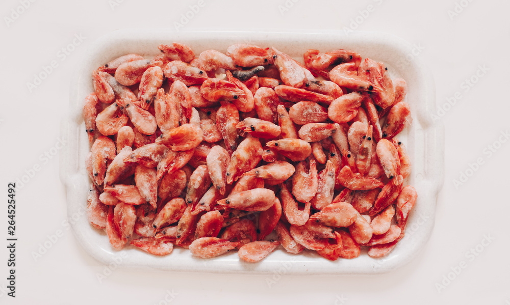 Raw shrimp background. Pile of frozen shrimps on white background.Close-up of frozen shrimps. Shrimp and ice, top view. Raw shrimp background. Pile of frozen shrimps on white background.Close-up of frozen shrimps. Shrimp and ice, top view.