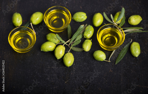 green olives, olive branch and olive oil on a dark wooden board
