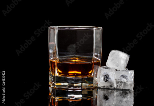 hexagonal glass of whiskey with ice on a dark background and a number of real ice cubes