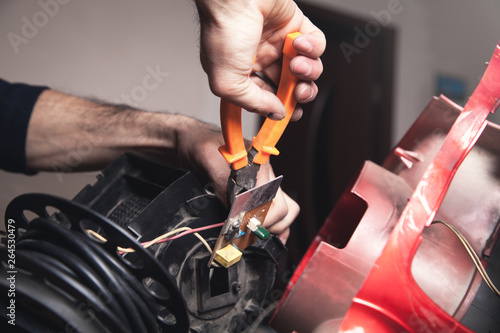 Electrician cutting cable with cutters.