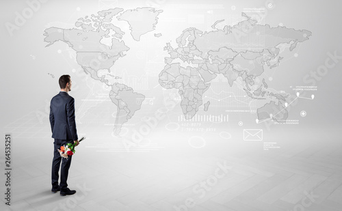 Businessman standing with his back and looking at a worldwide map with objects in his hand   © ra2 studio