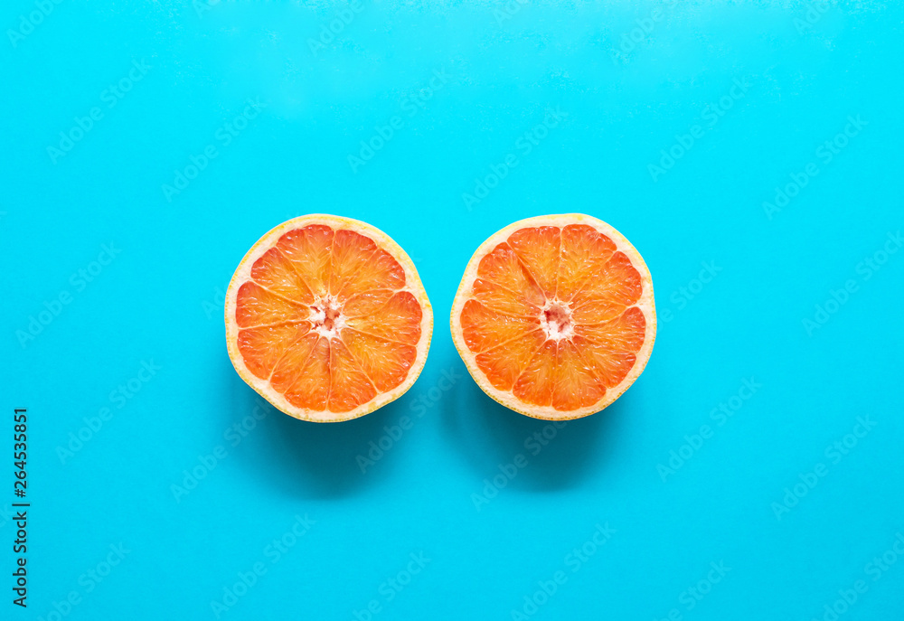 Two red orange grapefruit slices on blue background, flat lay, minimalism, summer creative concept Two red orange grapefruit slices on blue background, flat lay, minimalism, summer creative concept