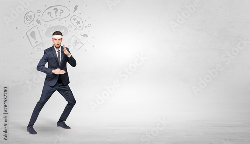 Young businessman in suit fighting with doodled symbols concept  