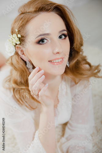 Beautiful girl with blond hair in a bright room is lying on the floor. Bride lying looking at the camera and smiling