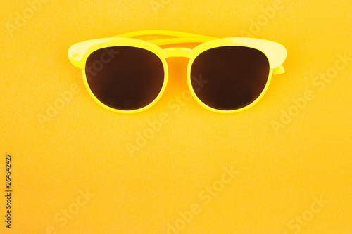 Yellow sunglasses isolated over the yellow background. Top view