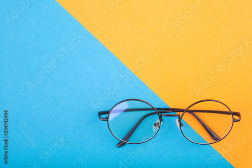 Round shaped glasses on yellow and blue background. Top view