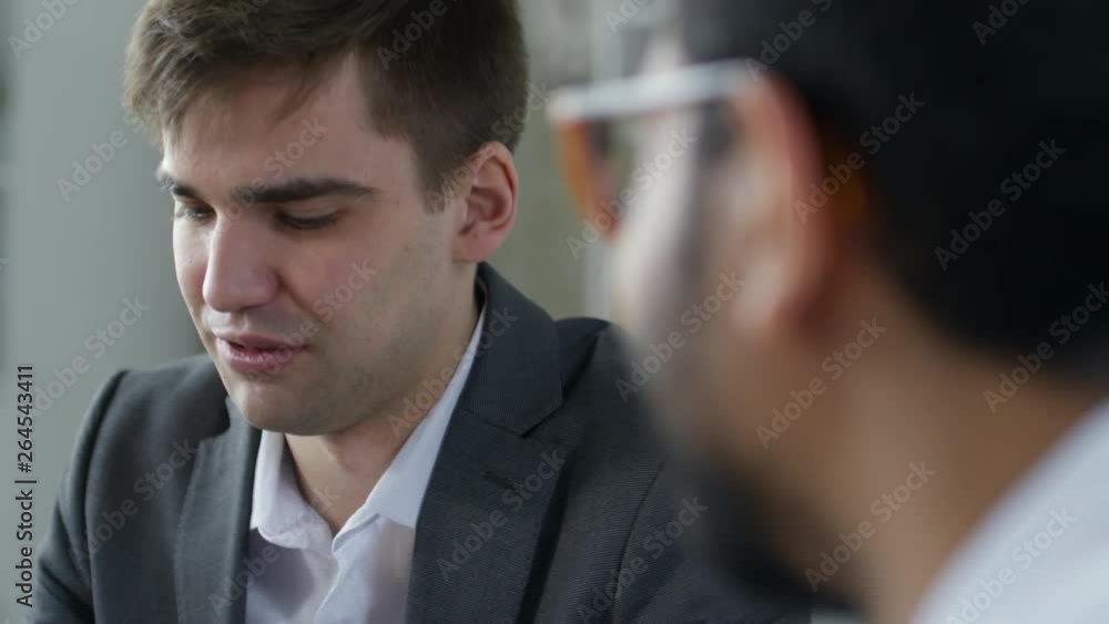 Tilt up shot of caucasian businessman in formal suit talking with colleagues during office meeting Tilt up shot of caucasian businessman in formal suit talking with colleagues during office meeting
