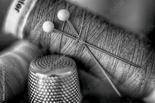 Black and white image of cotton reel, thread, pins and thimble photo