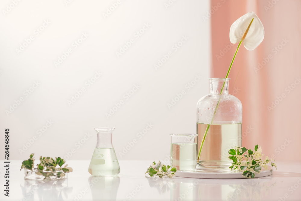 Perfume oils concept. Laboratory glassware with infused floral water on table Perfume oils concept. Laboratory glassware with infused floral water on table
