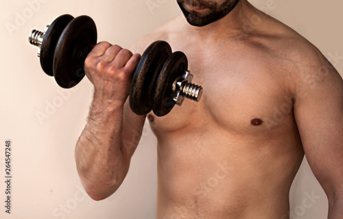 man shakes muscles with a dumbbell in his hand  torso close-up