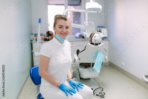 Young dentist in clinic stand in front of equipment and smile