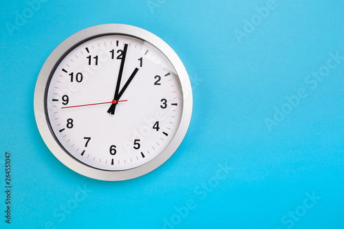 Closeup wall clock set on blue background. The concept of " The time is going on." Top view with Selective focus. Copy space.