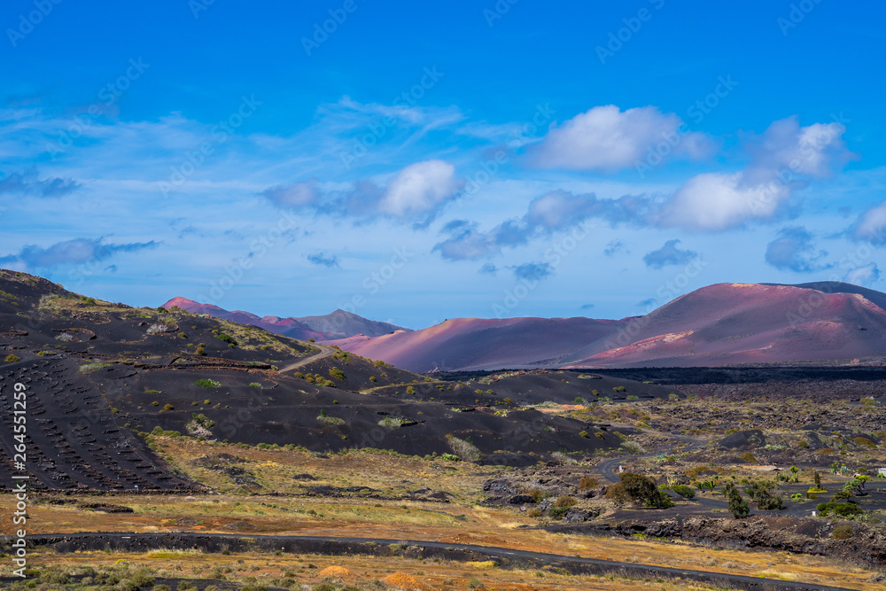 Spain, Lanzarote, Volcanic nature landscape of black and red volcano mountains and green fields
