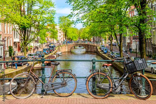 Photography Old bicycle on the bridge in Amsterdam, Netherlands against a canal during summer sunny day