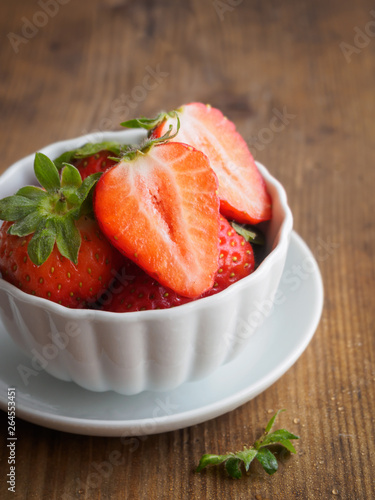 Frische Erdbeeren in einer weißen Schüssel auf einem braunen Holztisch