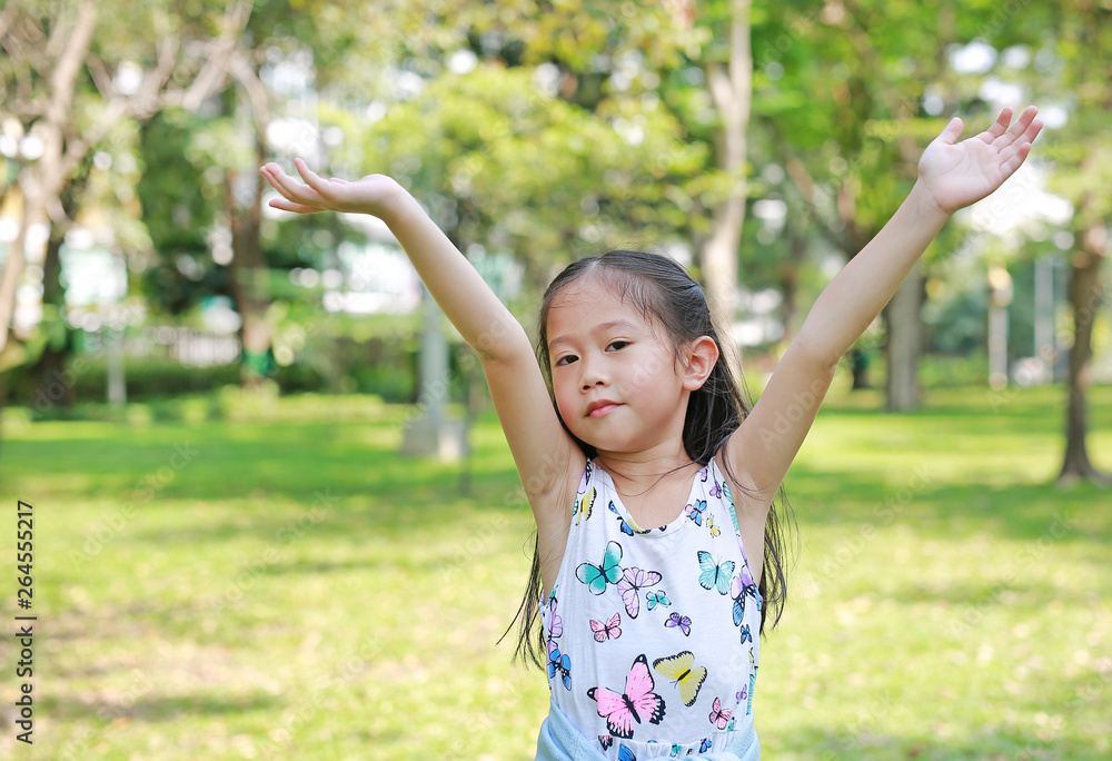 Happy little Asian child girl opened her hands in the summer park. Happy little Asian child girl opened her hands in the summer park.