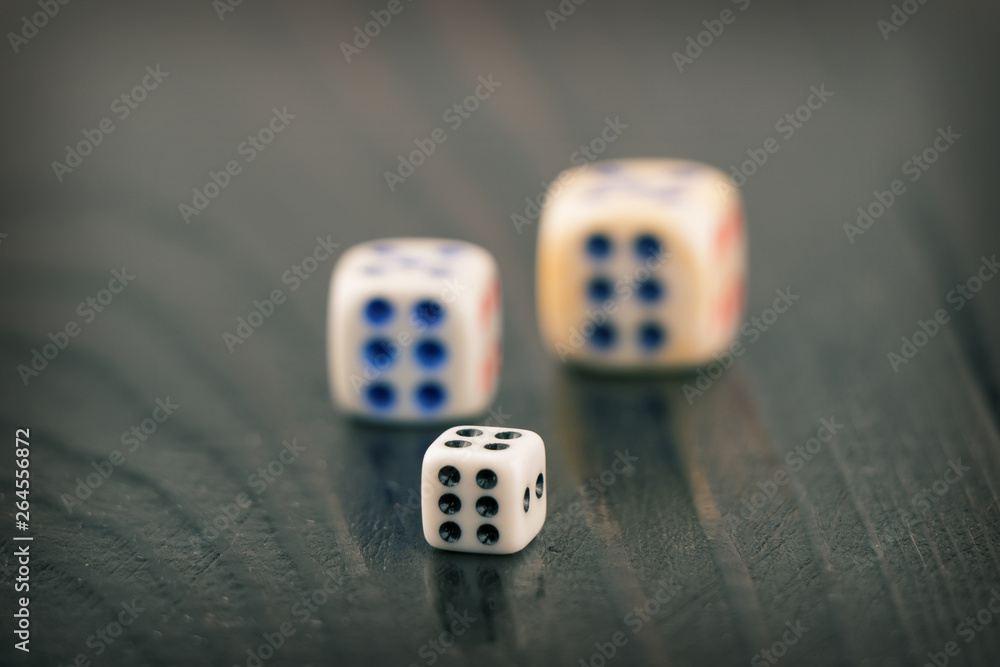 three dice of different sizes on a dark blurred background. toned three dice of different sizes on a dark blurred background. toned