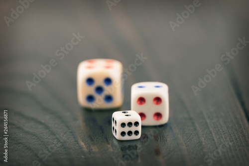 three dice of different sizes on a dark blurred background. toned