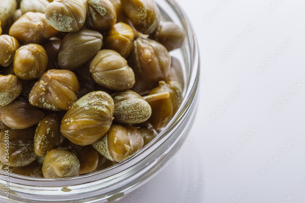 Pickled capers on a white acrylic background