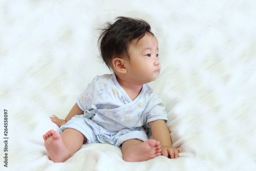 Asian cute baby, black and short hair, sitting on white mattress with curious and innocent face Asian cute baby, black and short hair, sitting on white mattress with curious and innocent face