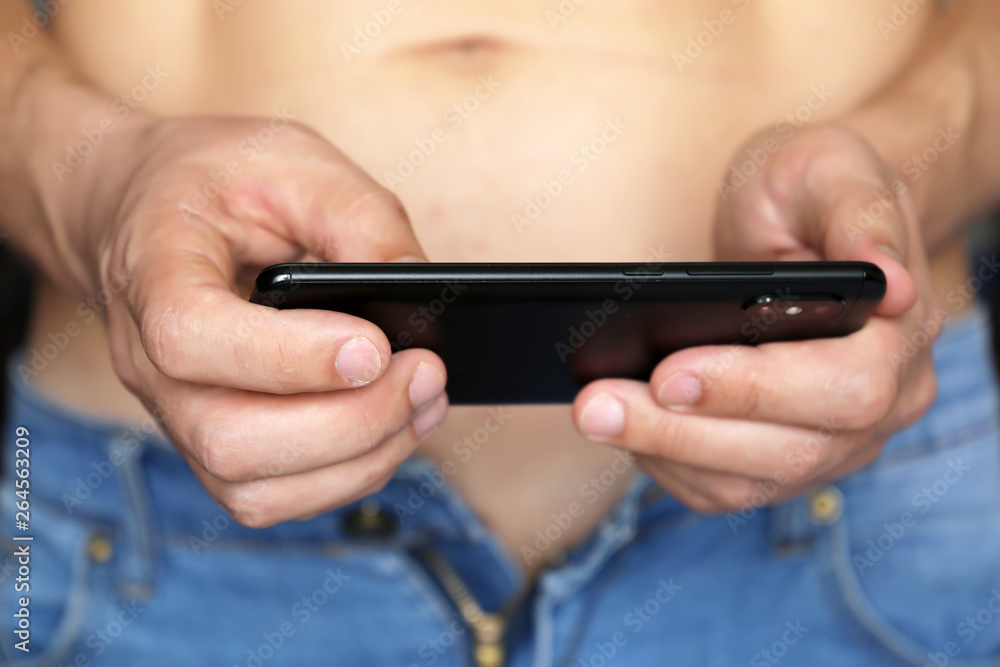 Www Sex Voed - Sporty man in unzipped jeans with smartphone in his hands. Concept of  watching porn video, playing mobile games at home, sex dating, online  communication, video chat Stock Photo | Adobe Stock