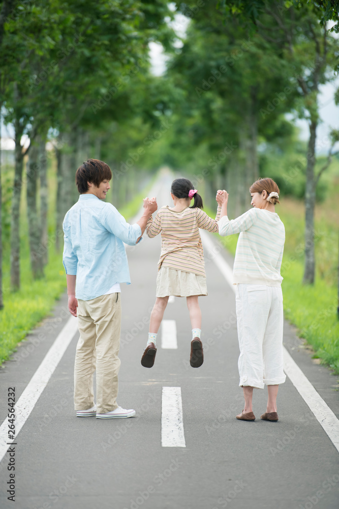 一本道で手をつなぐ親子の後姿 一本道で手をつなぐ親子の後姿