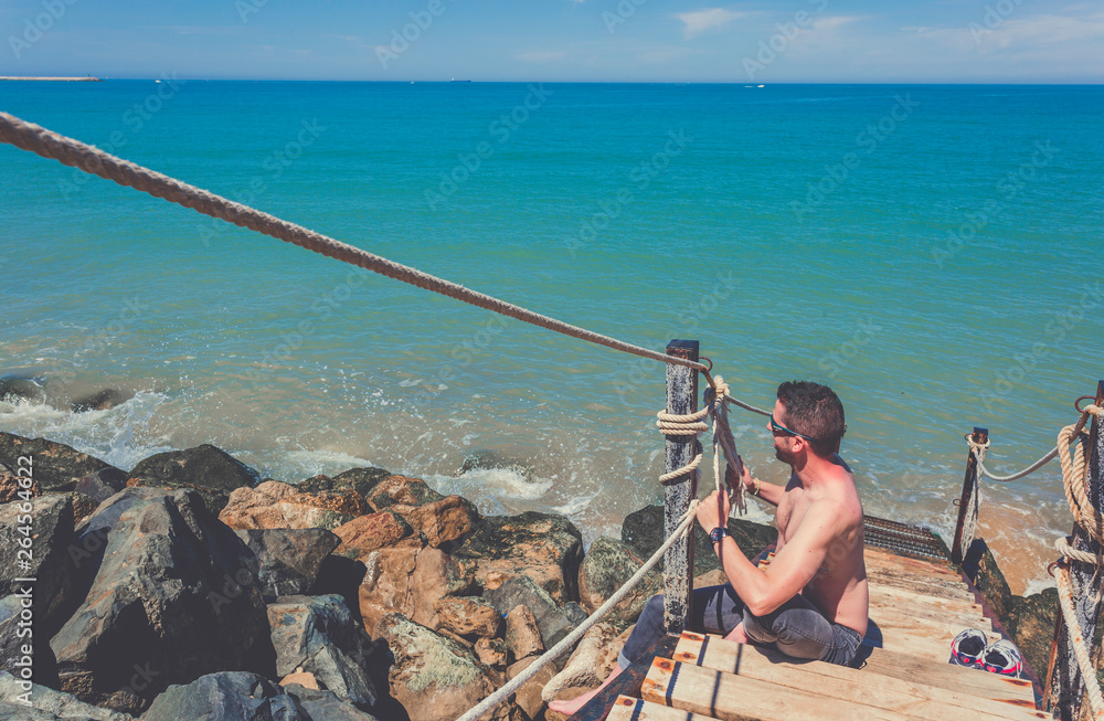 Obraz premium Caucasian young shirtless man making a great knot on strong rope