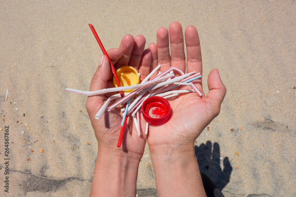Hands full of plastics on the beach. straws, ear swabs, plugs