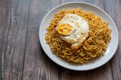 Fried curly noodle with fried egg on top of wooden table ready to be served.